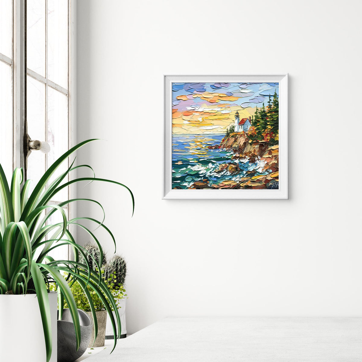 Acadia Lighthouse oil painting shown in a styled white frame beside green plants; artwork is sold unframed